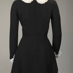 Back of long sleeved black wool mini dress. White collar and cuffs.
