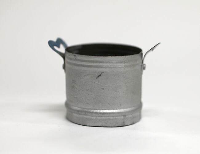 Side view of tiny aluminium pot with handles.