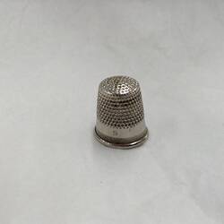 Small silver metal thimble.