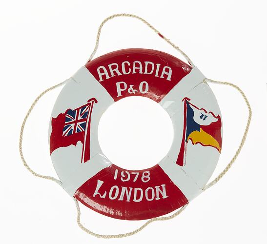 Red and white miniature lifebuoy with two flags painted on each side. Rope around rim.