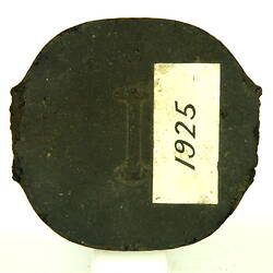 Black briquette with paper label.