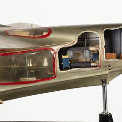 Green-silver model aeroplane on stand. Cutaways on side show interior.