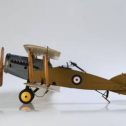 Model biplane aeroplane painted mustard brown with grey engine. Left side view.