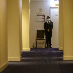 Digital Photograph - Security Guard at end of Hotel Corridor, Hotel Quarantine, Novotel on Collins, Melbourne, 13 May 2020