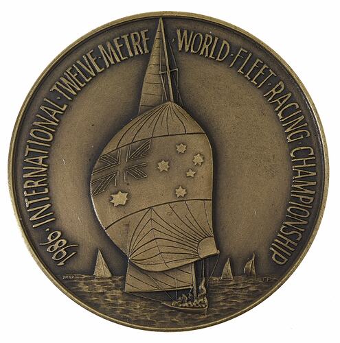 Round silver medal with yacht and spinniker bearing Australian flag. Text around.