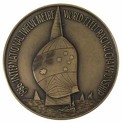 Round silver medal with yacht and spinniker bearing Australian flag. Text around.