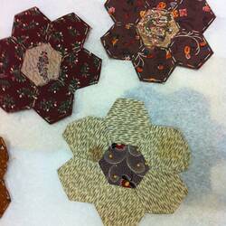 Hexagons of coloured fabric stitched together.
