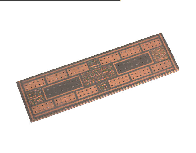 Front of rectangular cribbage board. Has holes punched throughout.
