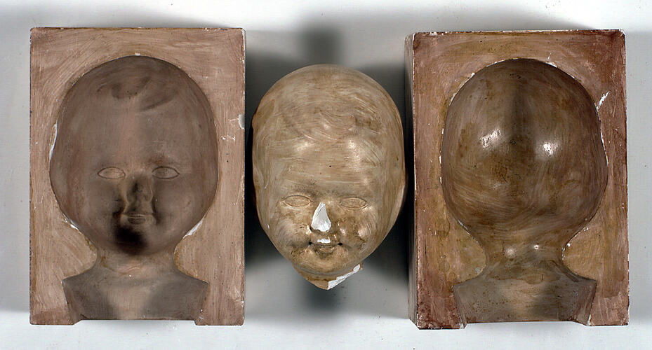 Two dolls' head moulds and one doll's head.