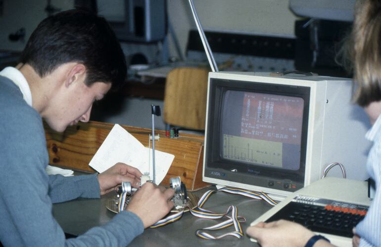 Young boy working on robotics in front of a computer.