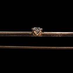 Profile of gold bar brooch with three gemstones. Purple amethyst at left end, diamond in centre and light green peridot at right end. Stamp on bar.