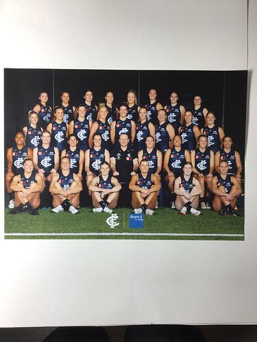 Group portrait of female footballers wearing blue jumpers with white logo.