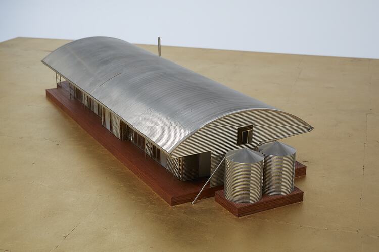 Model of a house with an arched roof, corrugated iron and wide expanses of glass.