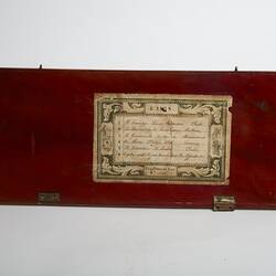 Wooden rectangular lid of box. Decorative paper label affixed.
