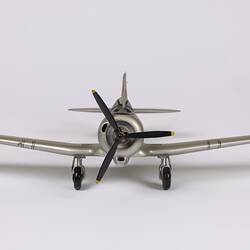 Silver model aeroplane. Front view. Black propeller and wheels.