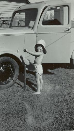 Digital Photograph - Boy in Sun Hat Pumping Air into Truck Tyre, Strathmore, 1950