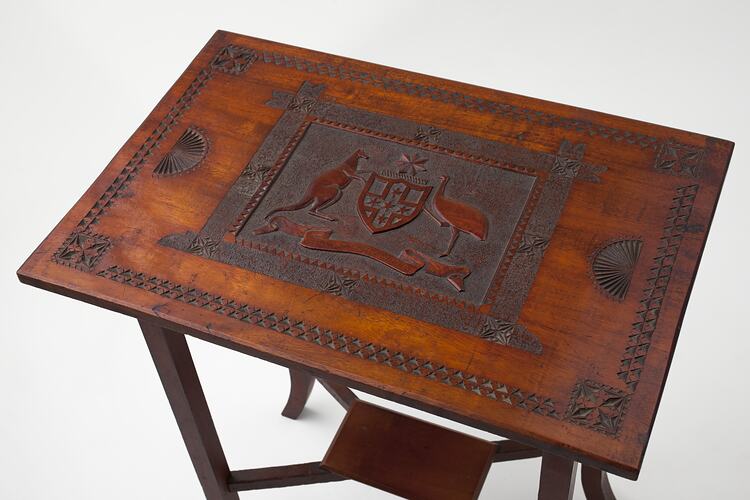 Wooden table viewed from above, Australian coat of arms carved into wood.