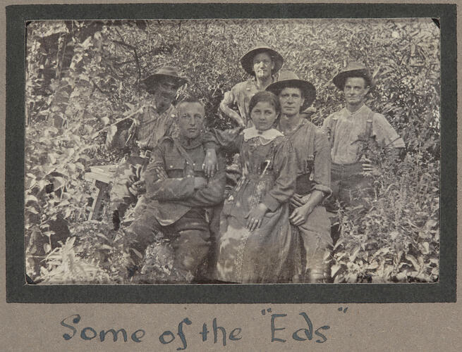 Group of servicemen and young girl surrounded by dense foliage.