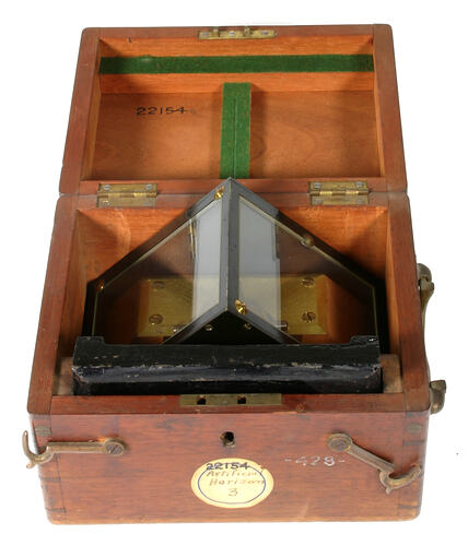 Open wooden box with black metal instrument inside.