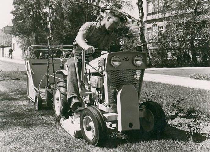 Front view of man driving a tractor in a park.