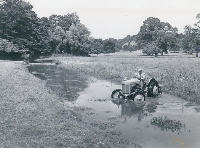 Man driving a tractor in a river.