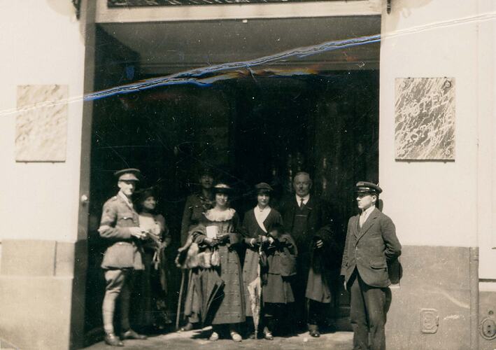 Group of men and women in front of hotel.