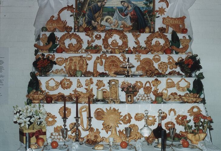 Five tiered table with display of different types of breads. Religious painting at top centre.
