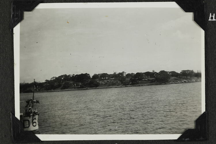 Water with part of ship in bottom-left corner, land in background.