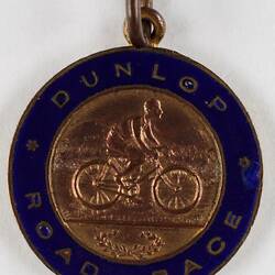Round medal with a cyclist in the centre.