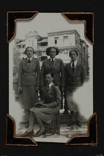 Four servicewomen on a balcony, three standing and one seated in front.