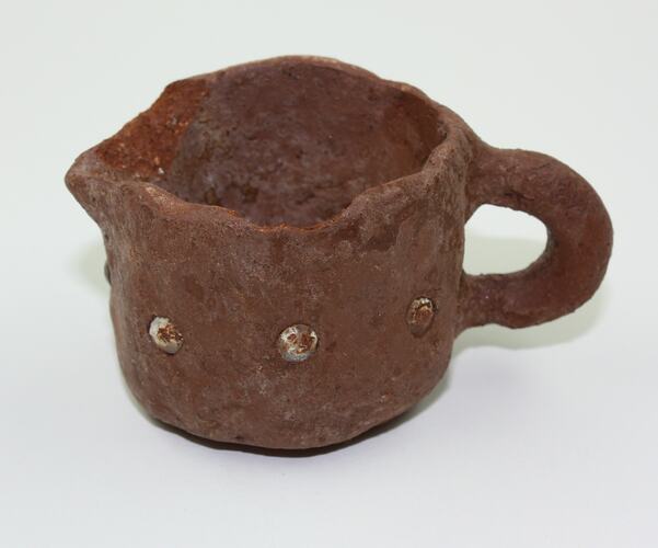 Clay toy milk pot viewed from side.