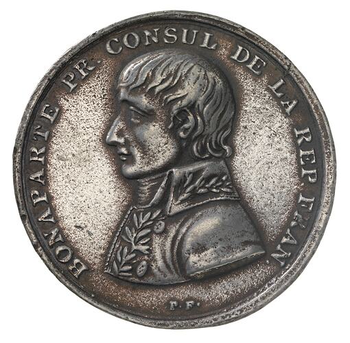 Round medal with male profile facing left.