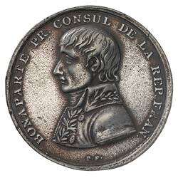 Round medal with male profile facing left.