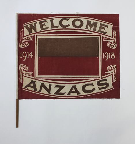 Red flag with off-white text 'Welcome Anzacs'.