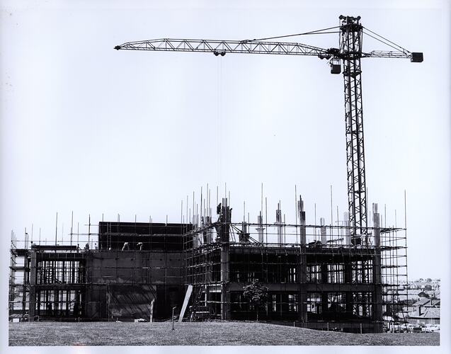 Crane above multistorey scaffolded construction site.