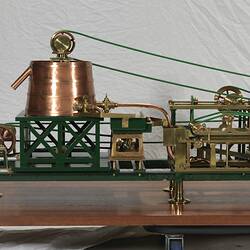 Paper making machine miniature model made of metal. Detail of copper drum at one end. Wooden base.
