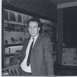 Man in suit with display case in background.