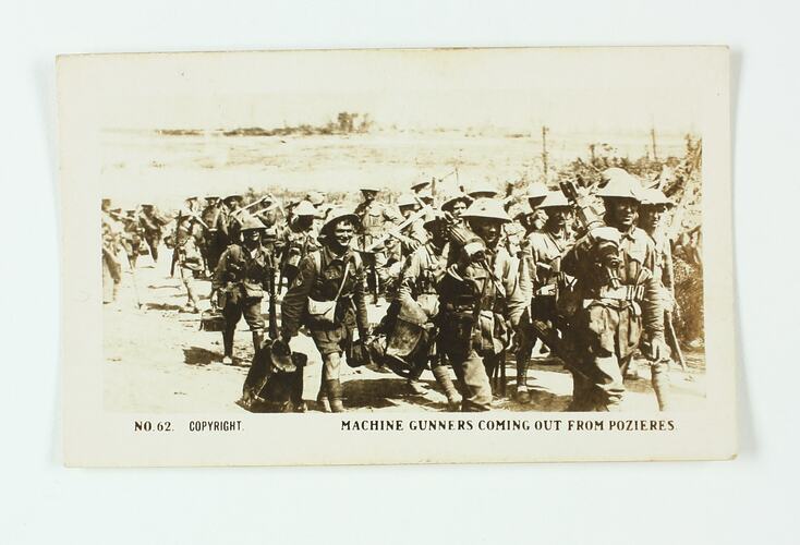 Group of servicemen walking on dirt road.