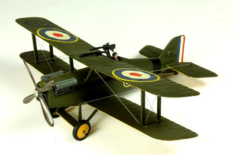Dark green model airplane. Circle pattern on top on each wing. Left profile.