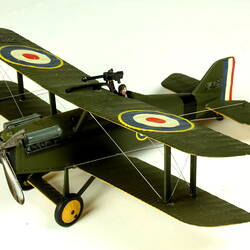 Dark green model airplane. Circle pattern on top on each wing. Left profile.