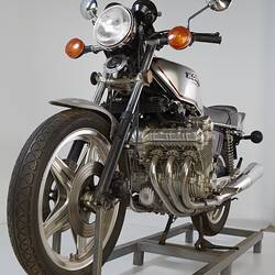 Silver motor cycle. Single headlight, round silver side mirrors and orange indicators.