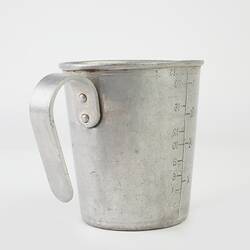 Tin measuring jug with handle, rear view.
