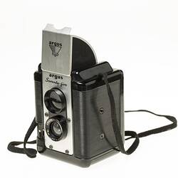 Black plastic box camera, black shoulder strap. Metal pop up viewfinder hood on top.