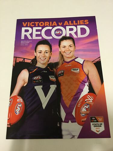 Booklet cover with two female footballers. One wears a navy jumper with a V, the other a red one.