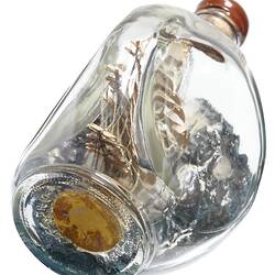 Model sailing ship in glass bottle. Underside has label.