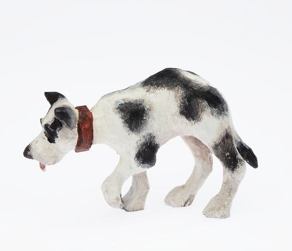 Black and white dog figurine with red collar and tongue. Profile.