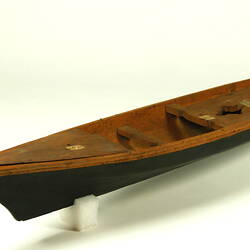 Wooden boat with black hull, three quarter view.