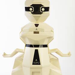 Cream plastic robot with angular human-like shape, ie. head, shoulders, waist and legs. Black plastic features. Arms out.