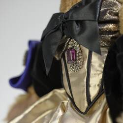 Detail of faux amethyst diamond pendant on black boned gold lame corset. Black bow neckline.