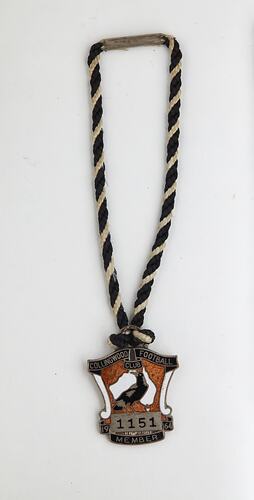 Shield-like shaped medal with magpie and black, white and brown enamel. Black, white twined cord. Silver text.